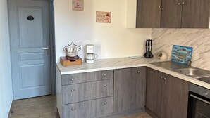 Een keuken met houten kastjes, een marmeren aanrechtblad, een koffiezetapparaat en een koffiekan.