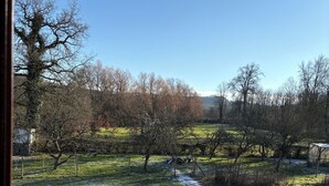 Uitzicht vanaf een balkon met een betegeld dak, op een met sneeuw bedekte tuin met bomen en een helderblauwe lucht.