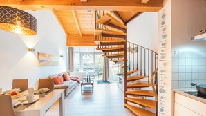 Ein modernes Interieur mit einer Holztreppe, einem Essbereich mit einem langen Tisch und einer Küche mit Herd.