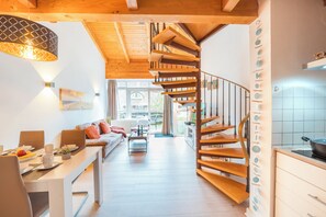 Ein modernes Interieur mit einer Holztreppe, einem Essbereich mit einem langen Tisch und einer Küche mit Herd.