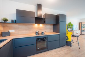 Eine moderne Küche mit dunklen Schränken, einer Holz Arbeitsplatte und integrierten Geräten, darunter eine Spülmaschine und ein Backofen.
