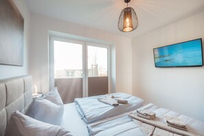Ein modernes Schlafzimmer mit großem Fenster, einem Bett mit ordentlich gefalteten Handtüchern und einem Gemälde an der Wand.