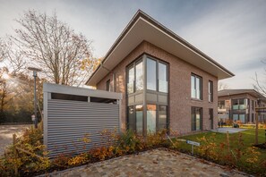 Ein modernes, zweistöckiges Haus mit Backsteinfassade, großen Fenstern und einer Garagentür.