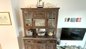 A wooden cabinet with multiple shelves and drawers, a television on a stand, and decorative items including a ship model and fish figurines. - Hello and welcome to Nordseeliebe! (Dangast)