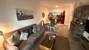 A living room with a grey sofa, a coffee table, and a painting of birds. - Hello and welcome to Nordseeliebe! (Dangast)