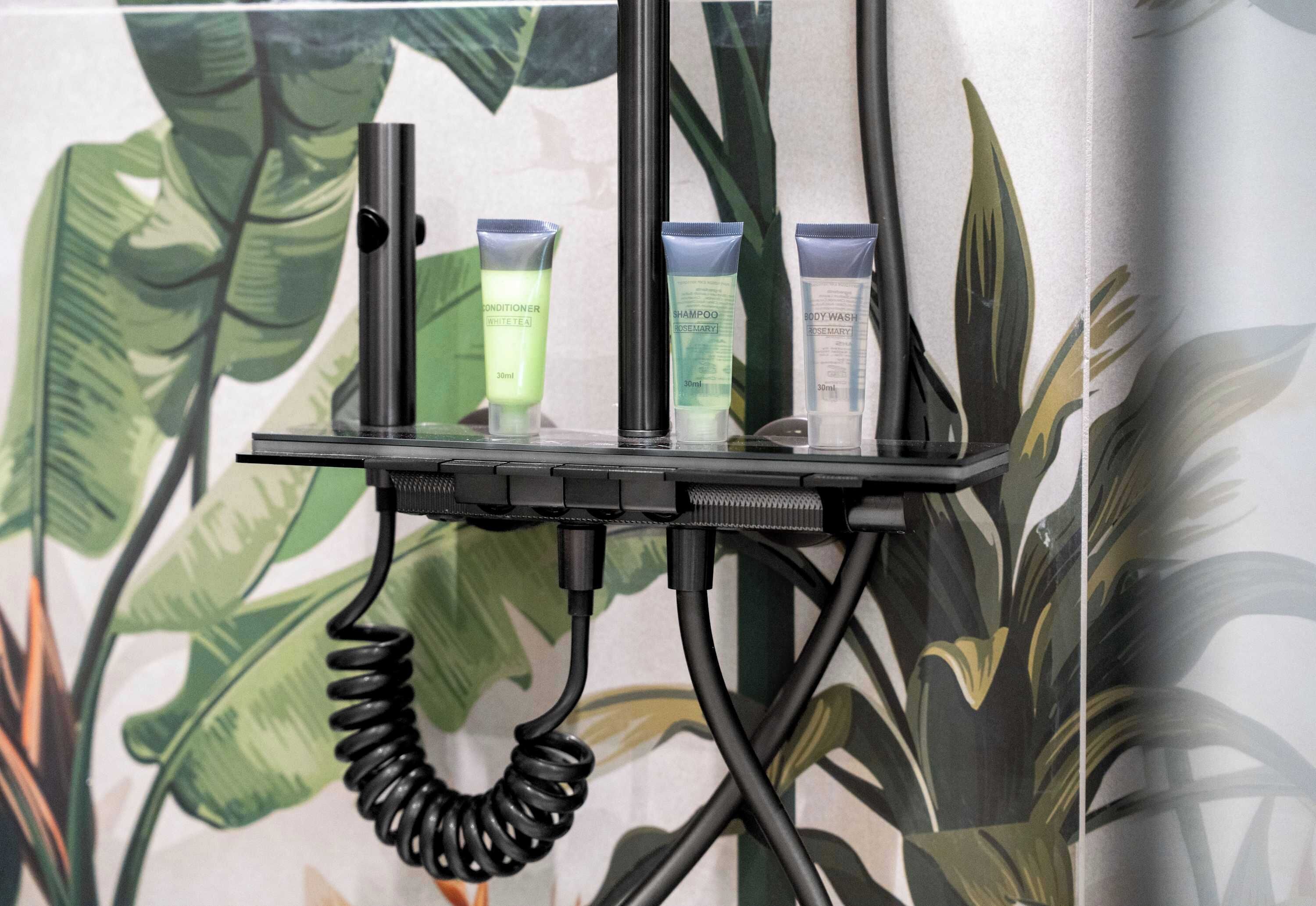 Een zwarte, opgerolde kabel verbonden met een standaard met drie persoonlijke verzorgingsproducten.
