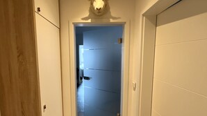 A hallway with a wooden door on the left, a blue door in the center, and a white door on the right. - Moin and welcome to Apartment Küstenglück! (Dangast)
