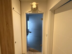 A hallway with a wooden door on the left, a blue door in the center, and a white door on the right. - Moin and welcome to Apartment Küstenglück! (Dangast)