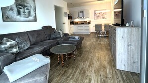 A modern living room with a sectional sofa, a round coffee table, and a TV. - Moin and welcome to Apartment Küstenglück! (Dangast)