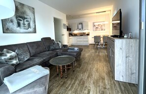 A modern living room with a sectional sofa, a round coffee table, and a TV. - Moin and welcome to Apartment Küstenglück! (Dangast)