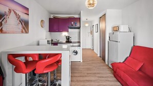 Un espacio habitable compacto con cocina, comedor y un sofá rojo.