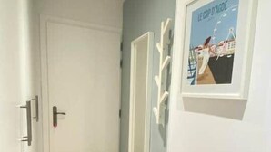 Ein Flur mit Holzboden, einer weißen Tür und einem gerahmten Bild an der Wand.