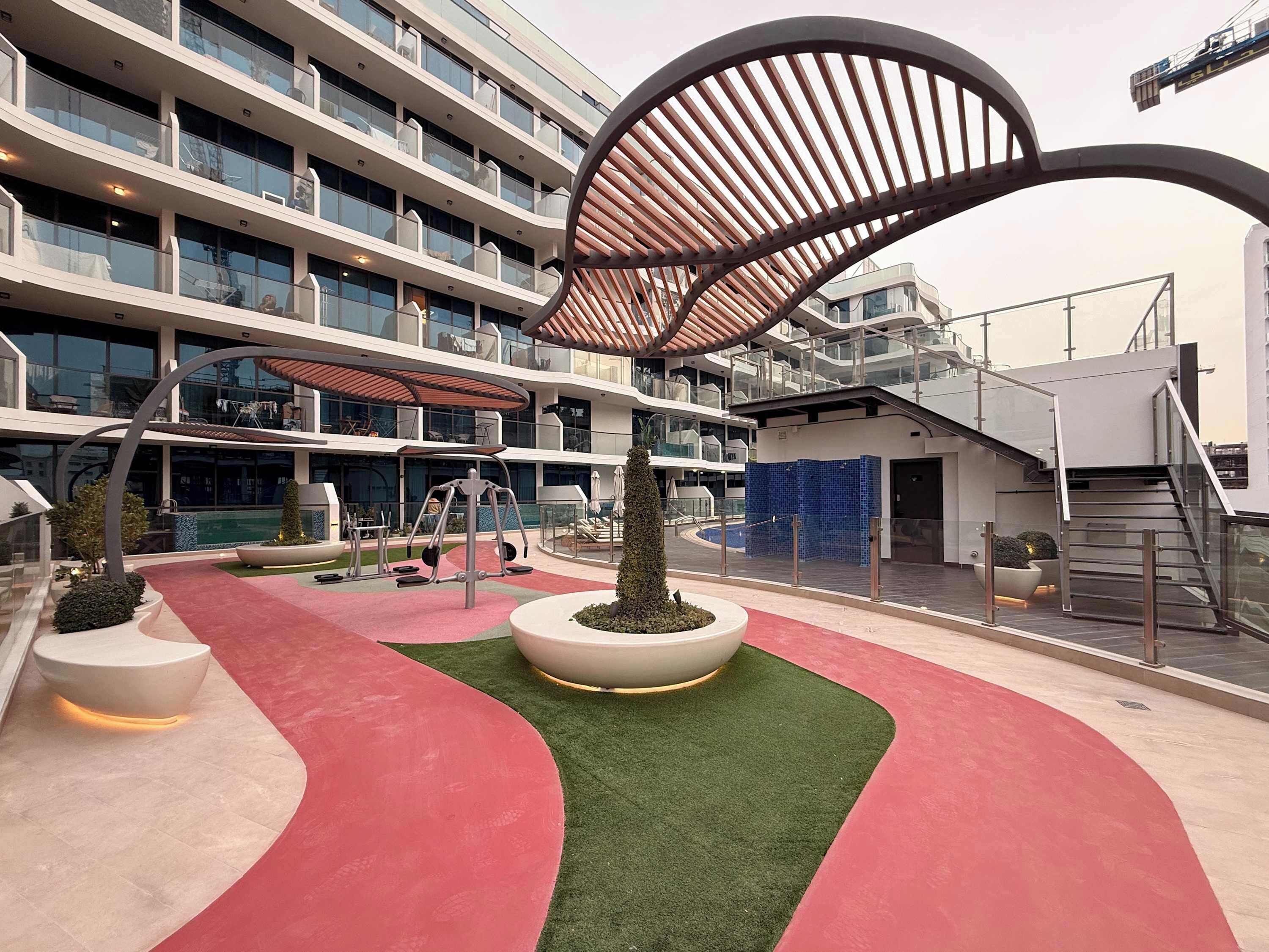 Un hôtel moderne doté d’une piscine sur le toit, d’un espace aménagé avec des équipements de fitness, d’un coin salon couvert et d’un escalier menant à un niveau supérieur.