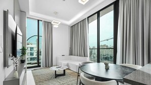 Ein modernes Wohnzimmer mit einem weißen Sofa, einem runden Couchtisch und einem Essbereich mit einem Glastisch und Stühlen.