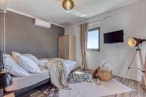 Une chambre à coucher moderne, équipée d’un lit, d’une armoire, d’un téléviseur et d’un lampadaire.