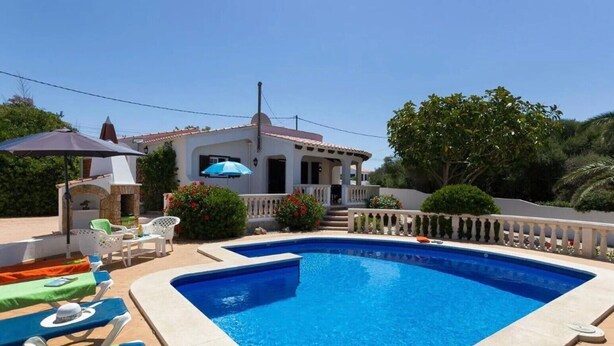Uma piscina com espreguiçadeiras e área de churrasco.