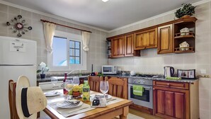 Cozinha com armários de madeira, mesa de jantar posta com pratos, copos e uma garrafa.