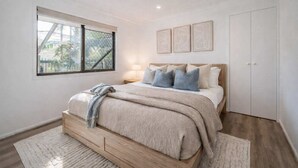 A bedroom with a bed, a window, and a door. - Serene Townsville Retreat with Pool & Alfresco, Sleeps 7 (Kirwan)