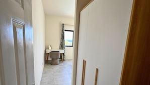 Ein Flur, der zu einem Schlafzimmer mit Bett, Schreibtisch und Stuhl führt.