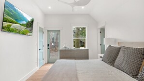 A bedroom with a bed, a dresser, a window, and a painting on the wall.