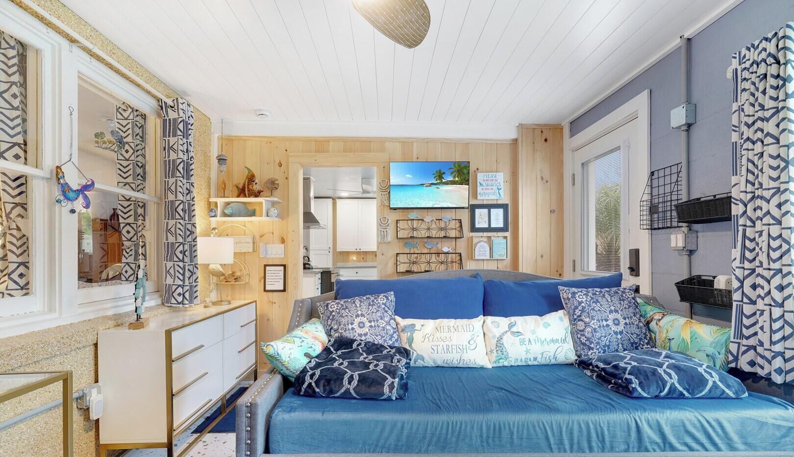 A bedroom with a bed, dresser, and a view of the beach through the window.