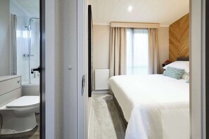 A modern hotel room with a shower, toilet, and a bed with a wooden headboard. - Host & Stay | Kingfisher Lodge, Amotherby (Amotherby)