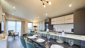 Een moderne keuken met een centraal kookeiland, een eethoek met stoelen en een bank.