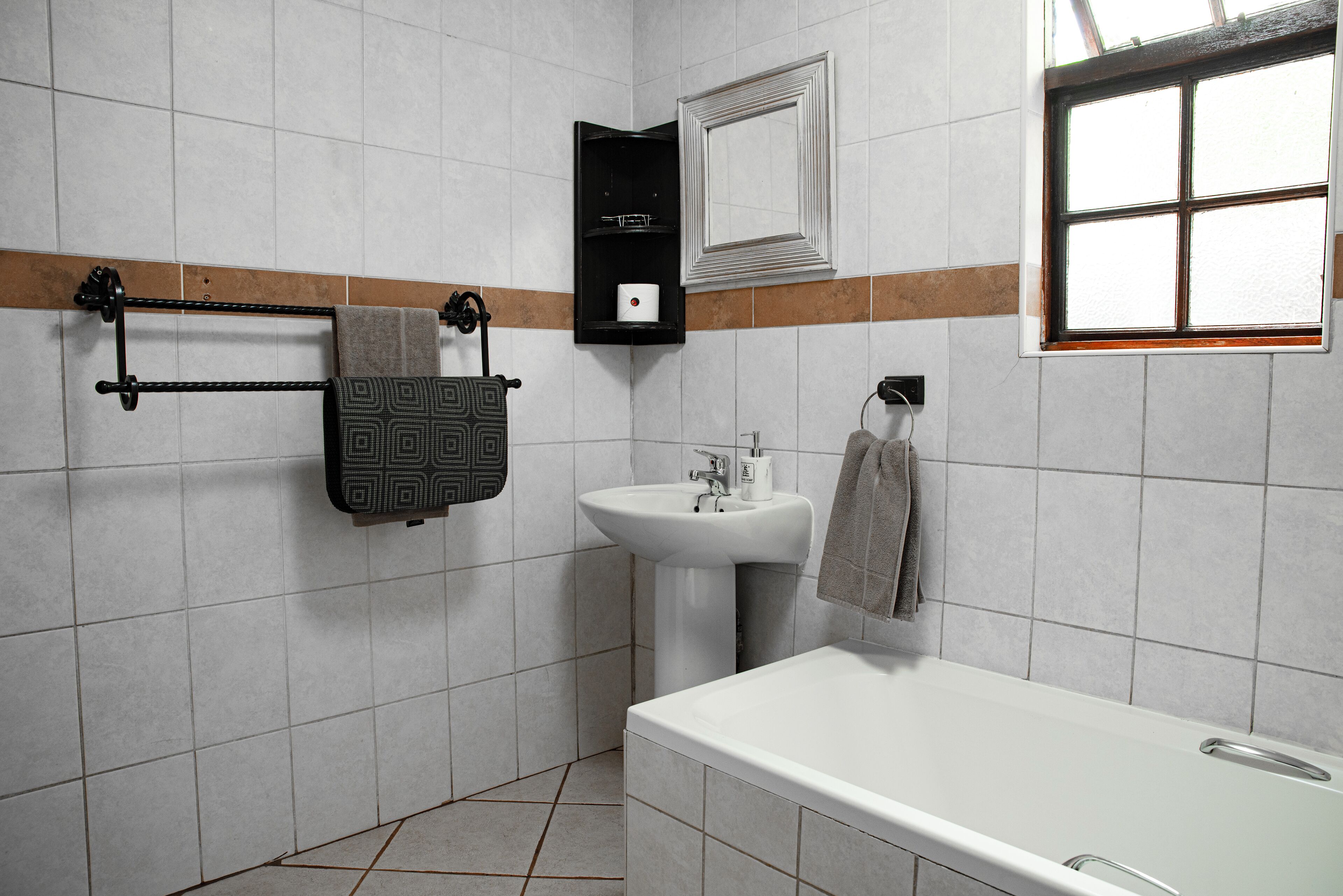A bathroom with a bathtub, a sink, and a towel rack.