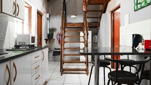 A kitchen with white cabinets, a wooden staircase, and a black countertop. - The Orion Guest House (Middelburg)