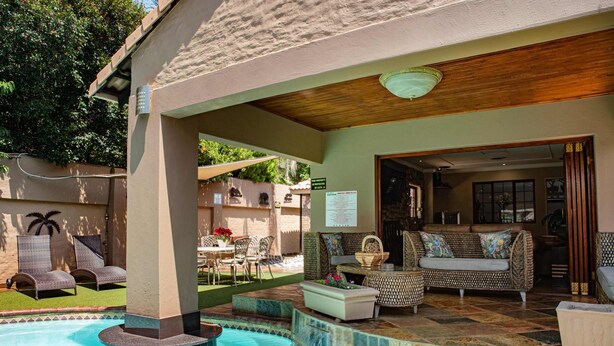 A pool area with a hot tub, lounge chairs, and a covered seating area with a sofa and coffee table. - The Orion Guest House (Middelburg)