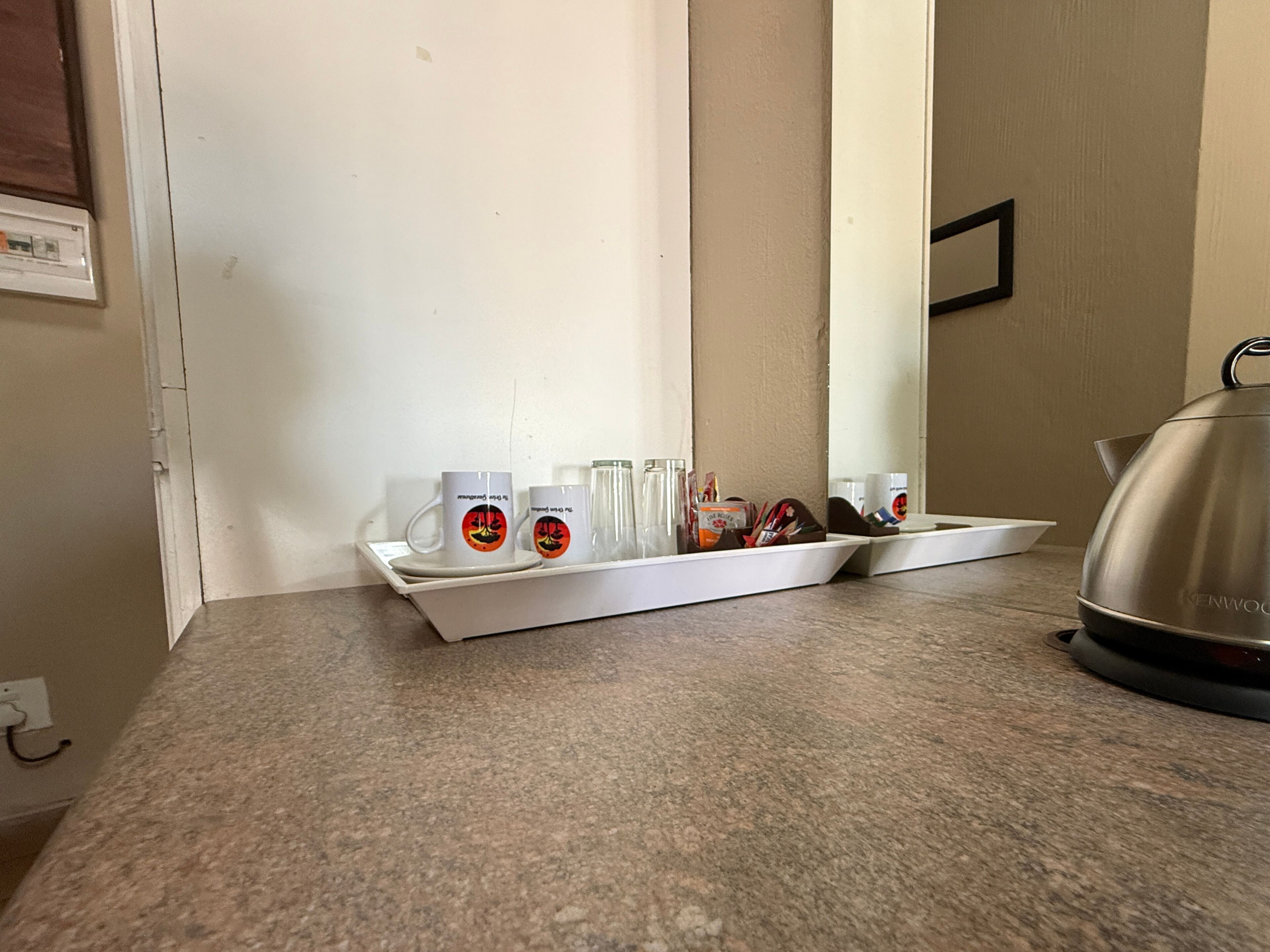 Un comptoir de cuisine sur lequel se trouve un plateau contenant deux tasses, un verre et une bouilloire.