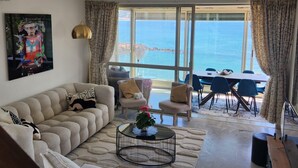 Una sala de estar con sofá, una mesa de centro y vistas al mar a través de amplios ventanales.