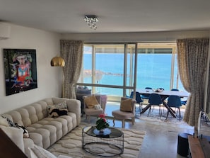 Ein Wohnzimmer mit einer Couch, einem Couchtisch und Meerblick durch große Fenster.