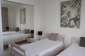 Un dormitorio con dos camas, un espejo grande y una obra de arte en la pared.