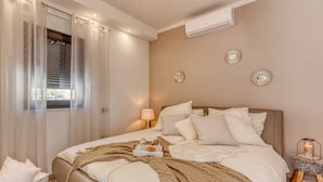 Une chambre à coucher comprenant un lit, une table de chevet, une lampe, des miroirs décoratifs et un appareil de climatisation.