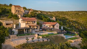 Une propriété située sur une colline, comprenant plusieurs bâtiments, une piscine et un jardin bien entretenu.