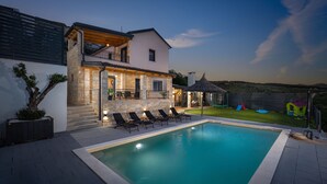 Une maison moderne dotée d’une piscine, d’un espace extérieur aménagé et d’un jardin bien entretenu.