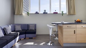 A modern living room with a sectional sofa, a bar area, and a window with curtains. - For Students Only Rooms in Plymouth (Plymouth)