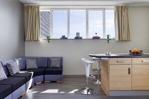 Ein modernes Wohnzimmer mit einem Ecksofa, einer Bar und einem Fenster mit Vorhängen.