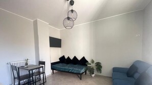 A compact living space with a dining table, a sofa, a radiator, and a hanging light fixture.