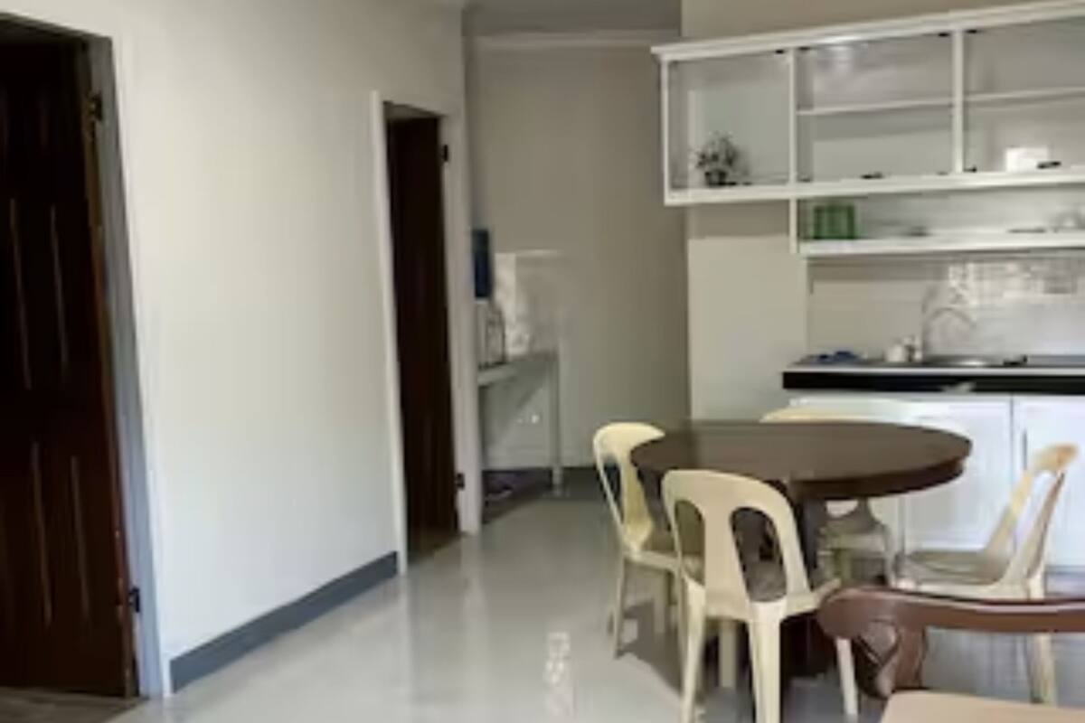 A modern kitchen with white cabinets and a dining area with a round table and plastic chairs.