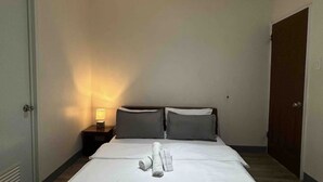 A hotel room with a neatly made bed, a bedside lamp, and a door. - Relaxing Resort Stay at Ashelma Resort (Dauis)