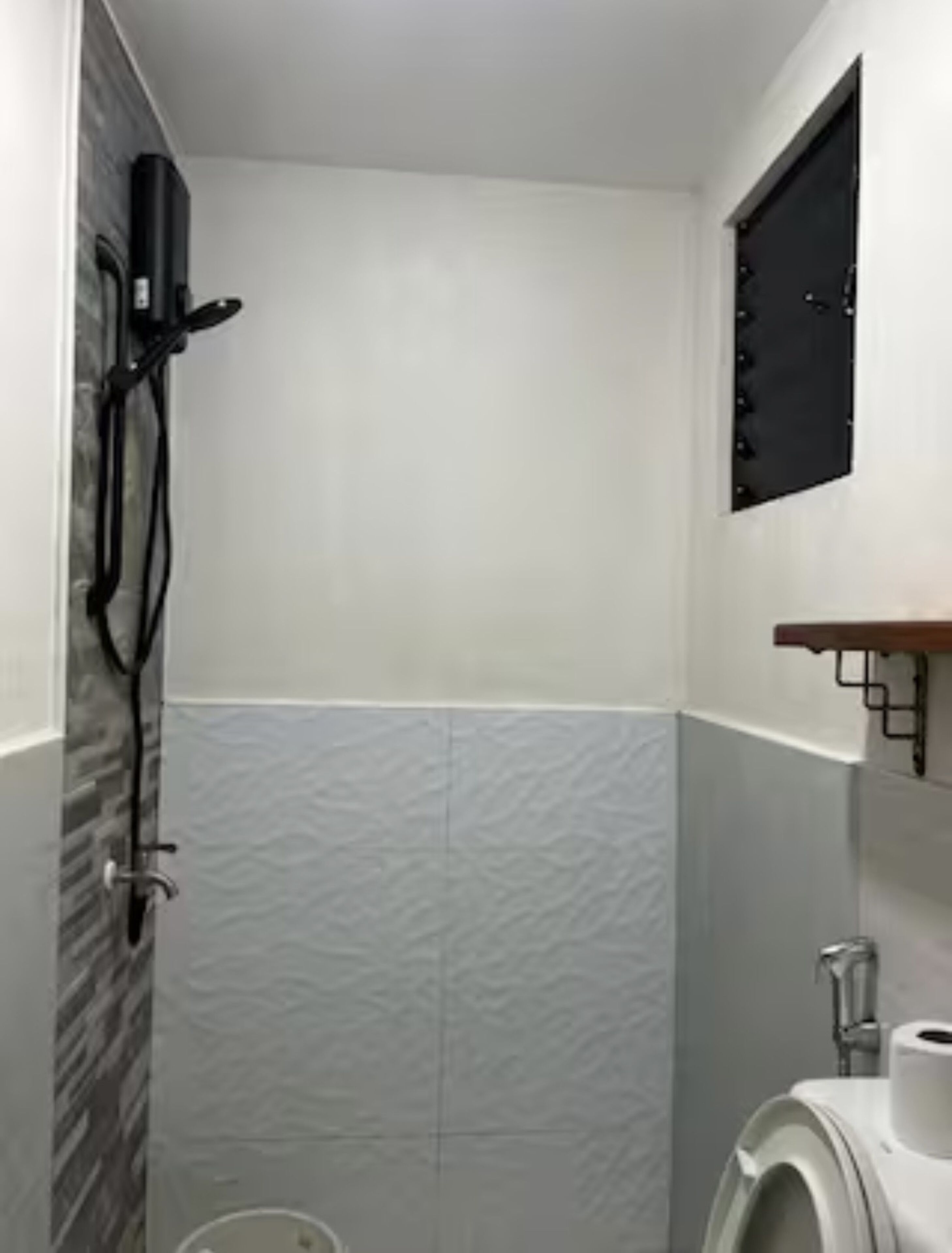 Ein Badezimmer mit Dusche, Toilette und einem Wandregal.
