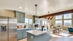 A modern kitchen with a large island, stainless steel appliances, and a view of the outdoors.
