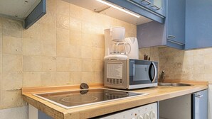 Una kitchenette equipada con microondas, cafetera y cocina a gas.