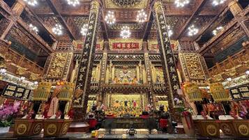 An ornate temple interior with intricate carvings and golden accents, featuring a central altar and multiple statues.