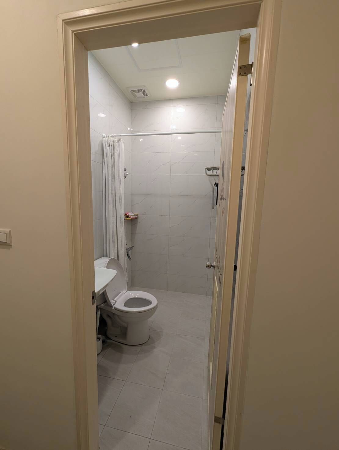 A bathroom with a toilet, shower, and a towel rack.
