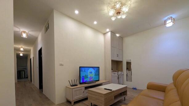 A modern living room with a television, a sofa, and a dining area. - Full 2B2B Accessible Home on the 1st Floor, Sleeps 5, in Xinyi District, Taipei. (Taipei City)