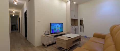 A modern living room with a television, a sofa, and a dining area.