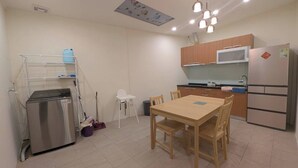 A compact kitchen with a dining table, a microwave, a refrigerator, and a small sink. - Full 2B2B Accessible Home on the 1st Floor, Sleeps 5, in Xinyi District, Taipei. (Taipei City)
